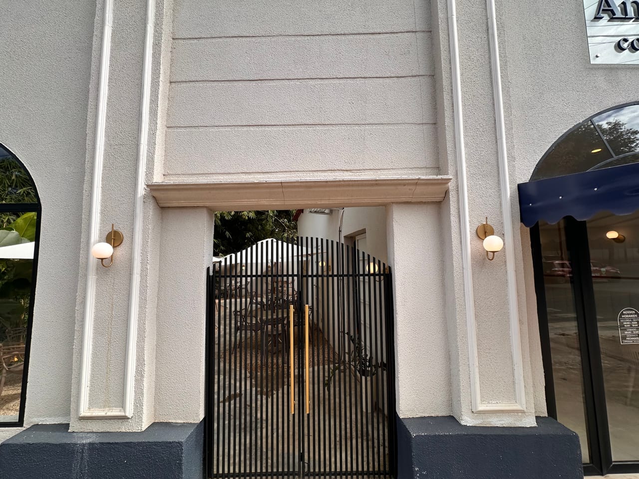 Entrada da cafeteria com portão de ferro e detalhes em latão, Uruaçu-GO